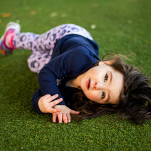 Young girl lying on astro turf