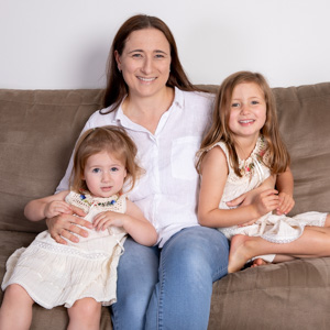 A mother and her two daughters sitting on a couch.  