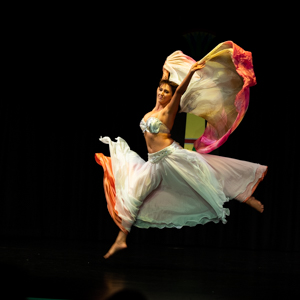 Dancer leaping through the air holding silk veil